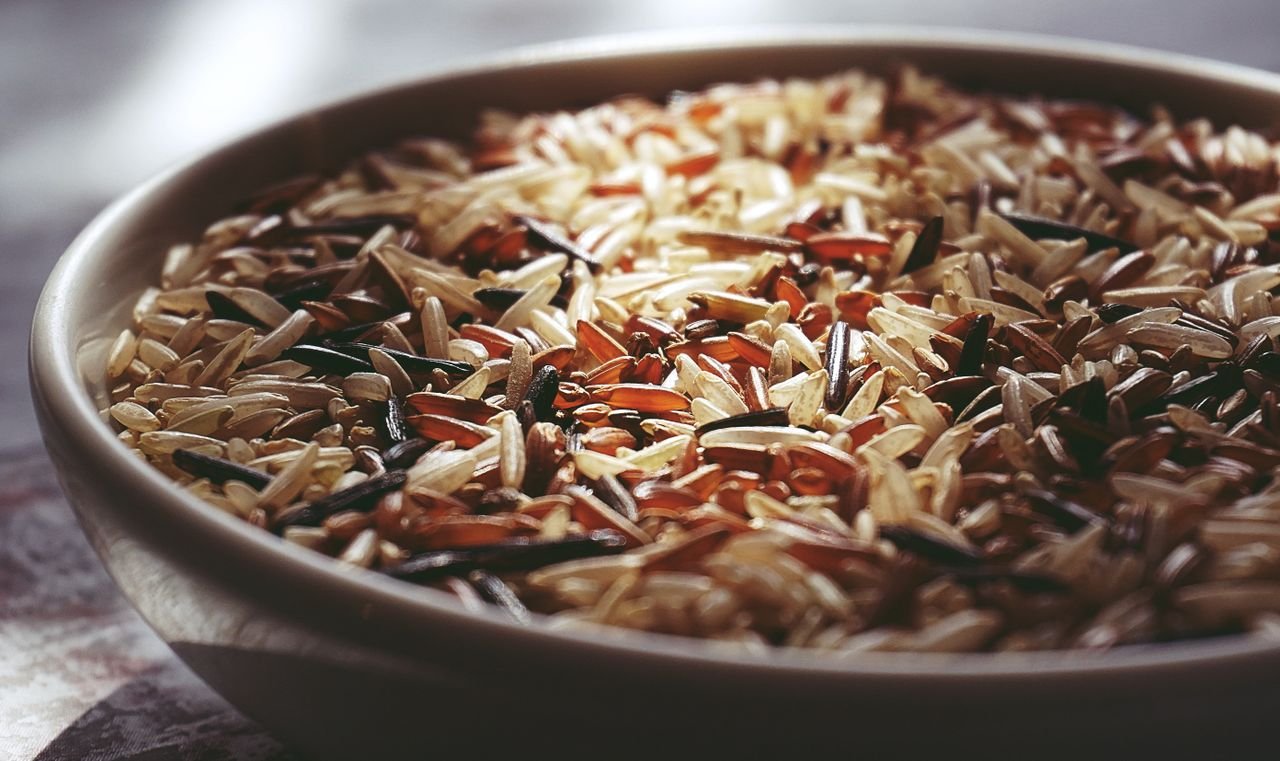 Macro shot of a ceramic bowl filled with colorful mixed wild rice, highlighting textures.