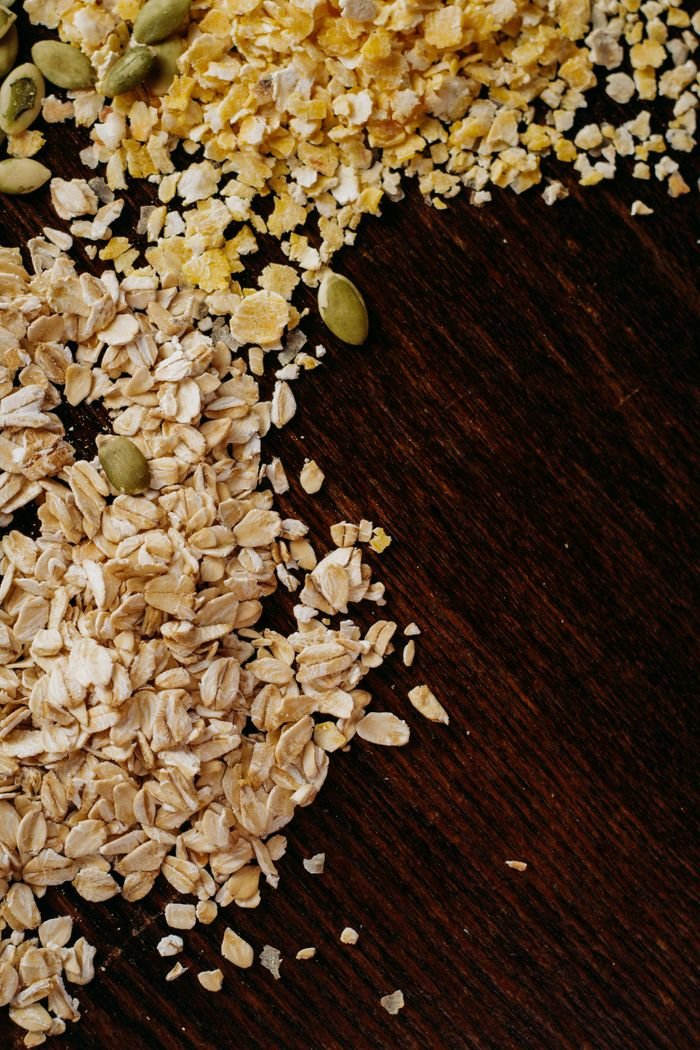High-angle view of oats, cornmeal, and seeds on a dark wooden table. Perfect for healthy food themes.