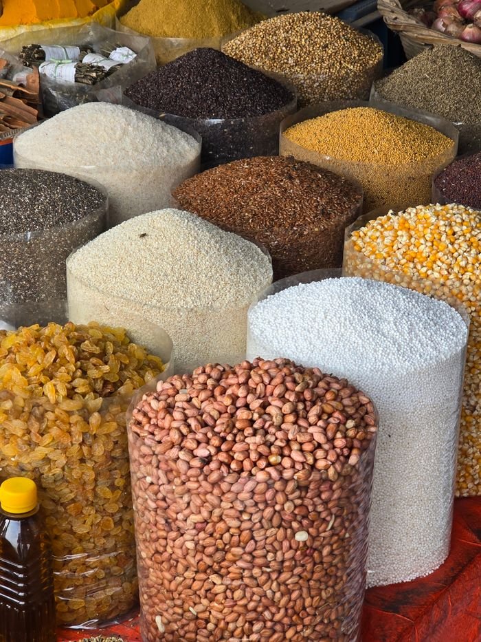 An array of grains and seeds on display in a Dhaka market, showcasing diverse textures and colors.
