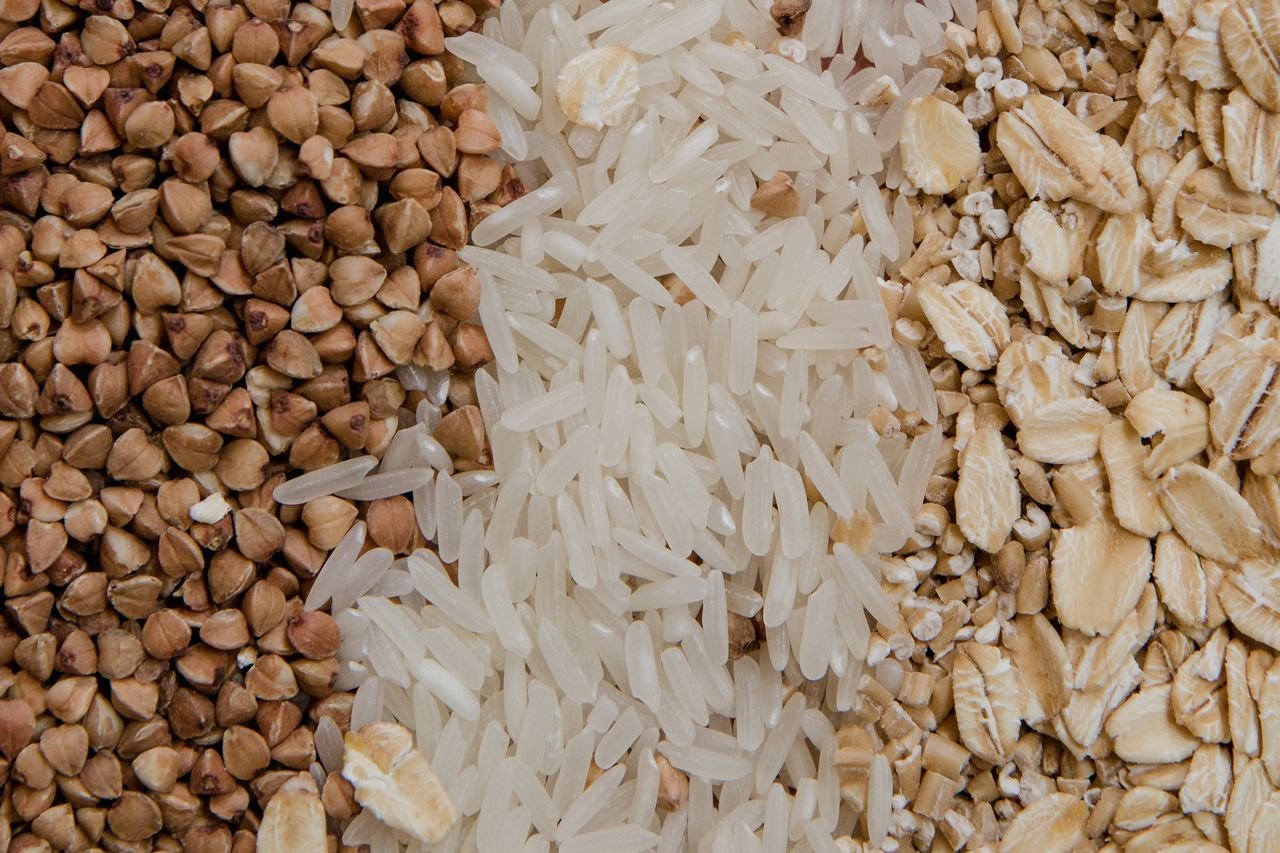 Close-up of assorted raw grains including buckwheat, rice, and oats, highlighting healthy food choices.